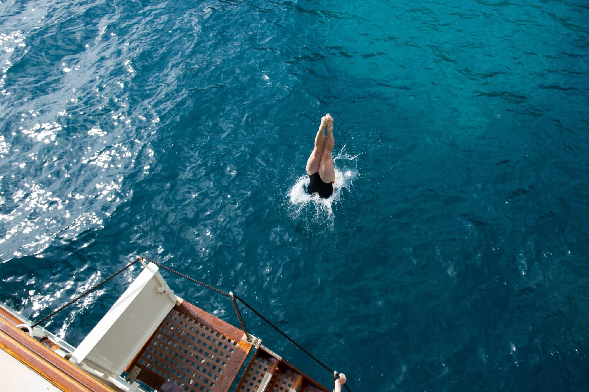 woman diving from a boat into the sea in majorca