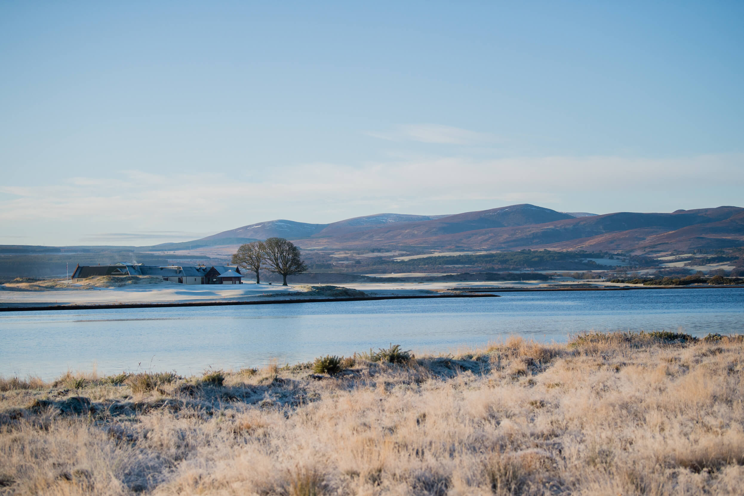 the clubhouse and lake at skibo castle in scotland during the winter with blue sky